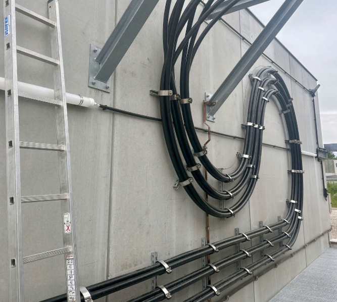Cables fixed to a concrete wall with clamps and supports