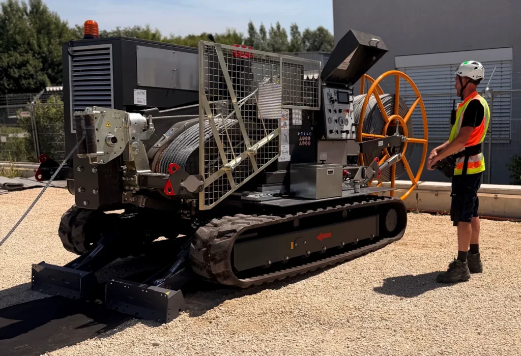 Employee operating a crawler-mounted cable pulling winch