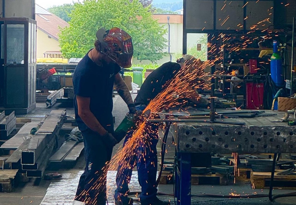 Employee grinding a steel component with visible sparks