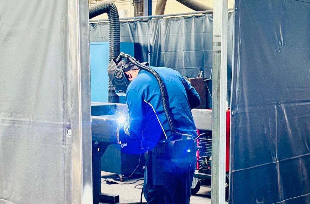 Welder wearing a protective helmet while welding a steel structure