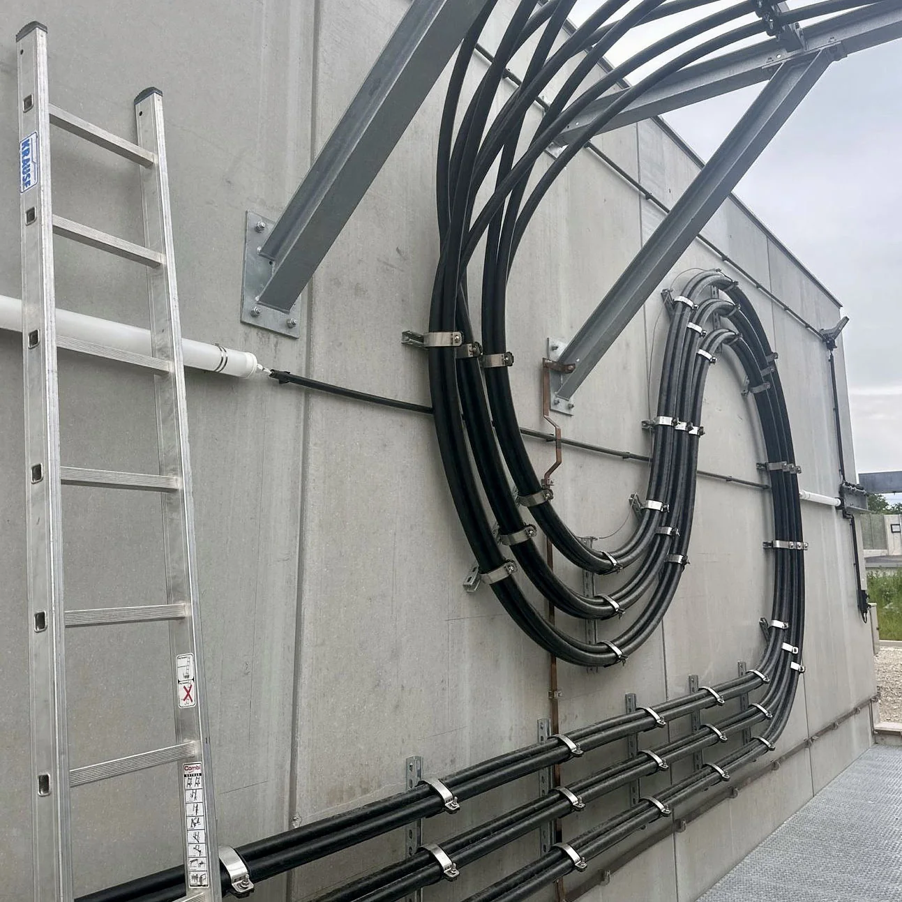 Kabel mit Schellen und Halterungen an einer Betonwand
